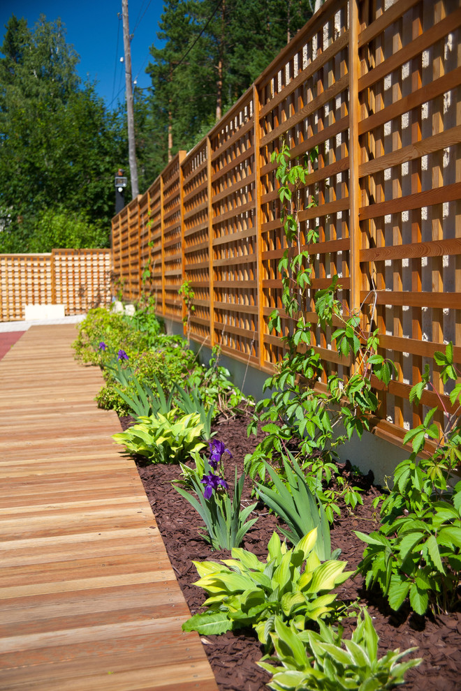 Cette image montre un jardin arrière design l'été avec une exposition ensoleillée et une terrasse en bois.