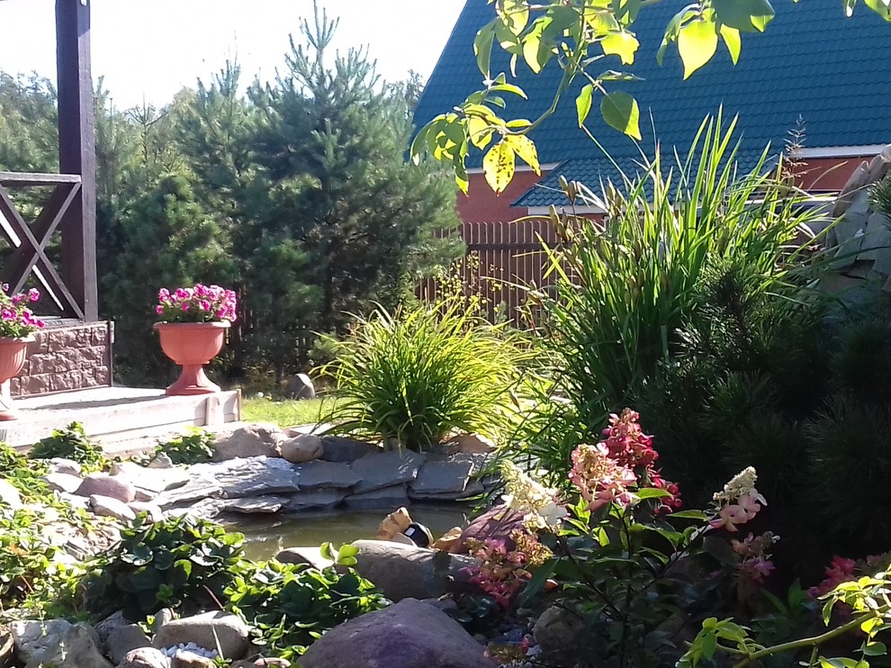 Modelo de jardín de estilo de casa de campo en verano en patio delantero con exposición parcial al sol