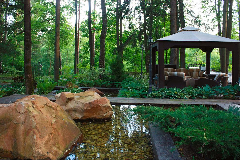 Imagen de jardín de estilo zen grande en verano en ladera con exposición parcial al sol, adoquines de piedra natural, jardín francés y roca decorativa