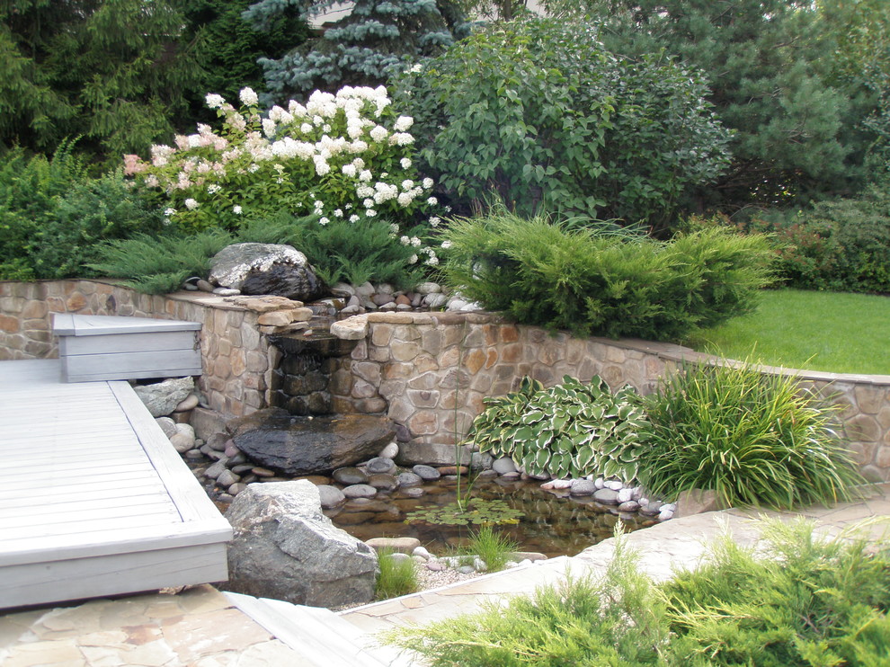 Diseño de jardín actual en verano en patio trasero con estanque, exposición total al sol, jardín francés y adoquines de piedra natural