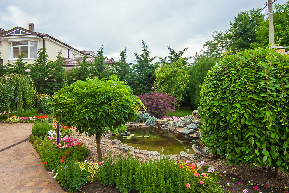 Imagen de jardín tradicional renovado en verano en patio trasero con estanque, exposición parcial al sol, jardín francés y adoquines de ladrillo