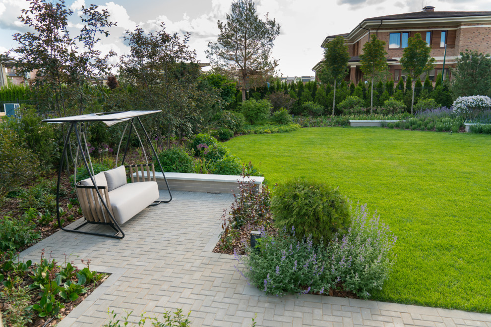 Свежая идея для дизайна: солнечный, весенний участок и сад среднего размера на внутреннем дворе в стиле модернизм с хорошей освещенностью, мощением тротуарной плиткой и подпорной стенкой - отличное фото интерьера