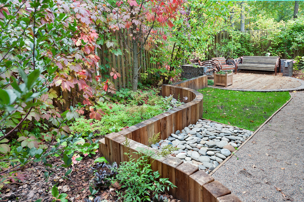 Foto di un giardino minimal esposto in pieno sole in autunno con un muro di contenimento