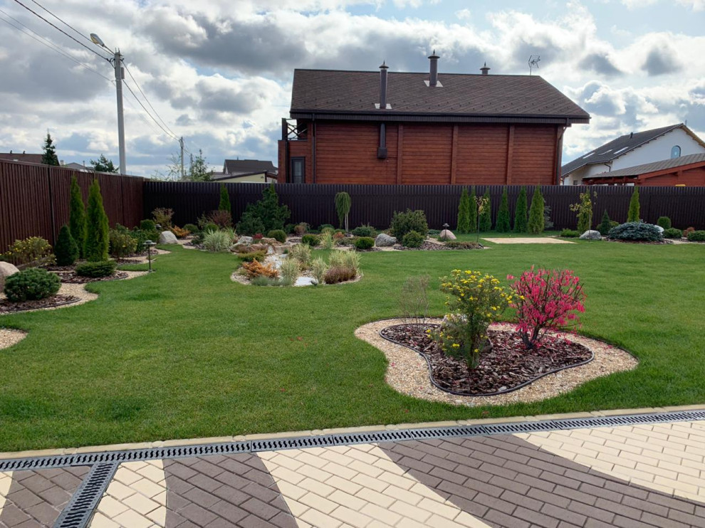 На фото: маленький солнечный, осенний засухоустойчивый сад на переднем дворе в стиле неоклассика (современная классика) с камнем в ландшафтном дизайне, хорошей освещенностью и покрытием из гальки для на участке и в саду с
