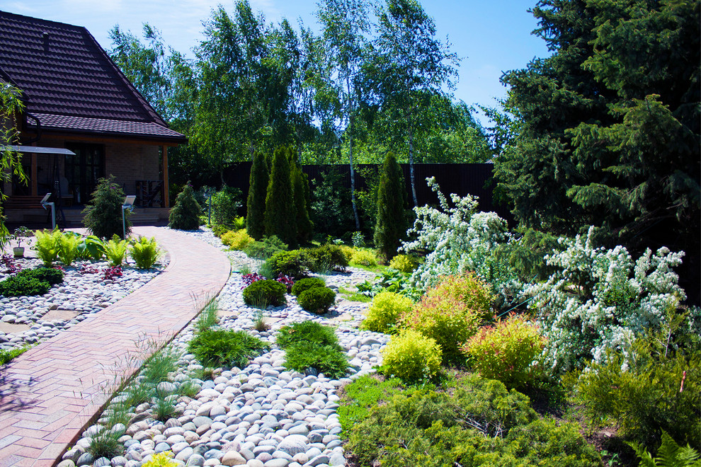 Immagine di un piccolo giardino mediterraneo esposto in pieno sole in cortile in primavera con pavimentazioni in mattoni