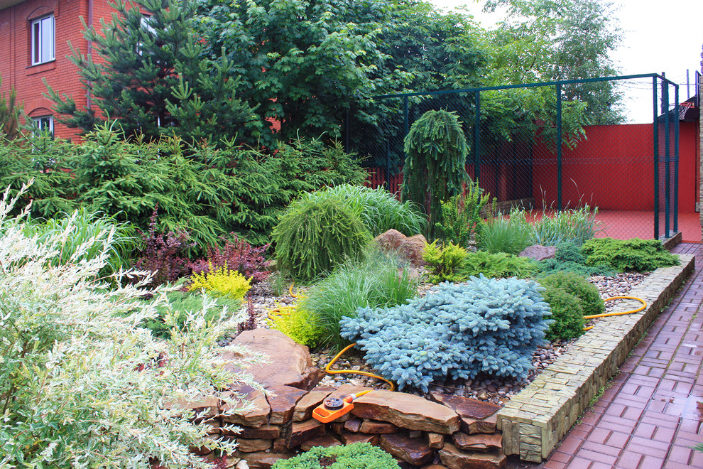 На фото: маленький летний регулярный сад на боковом дворе в стиле модернизм с полуденной тенью, мощением тротуарной плиткой и камнем в ландшафтном дизайне для на участке и в саду