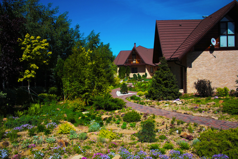 Immagine di un grande giardino xeriscape contemporaneo esposto in pieno sole in primavera con pavimentazioni in mattoni, sassi e rocce e un pendio, una collina o una riva