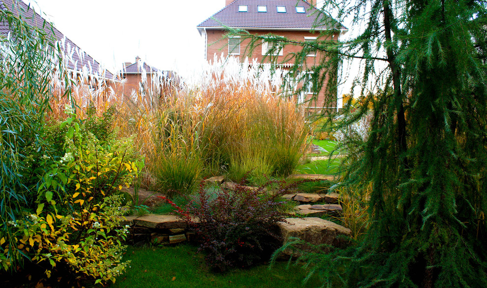 Diseño de jardín de secano clásico de tamaño medio en otoño en patio con muro de contención, exposición parcial al sol y adoquines de piedra natural