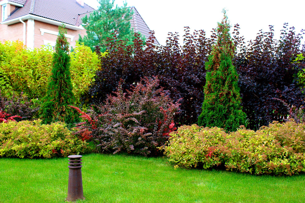 Пример оригинального дизайна: маленький осенний регулярный сад на боковом дворе в стиле неоклассика (современная классика) с мощением тротуарной плиткой, полуденной тенью и перегородкой для приватности для на участке и в саду
