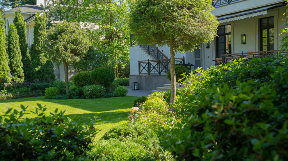 Modelo de jardín clásico de tamaño medio en verano en patio con exposición parcial al sol, adoquines de piedra natural y jardín francés