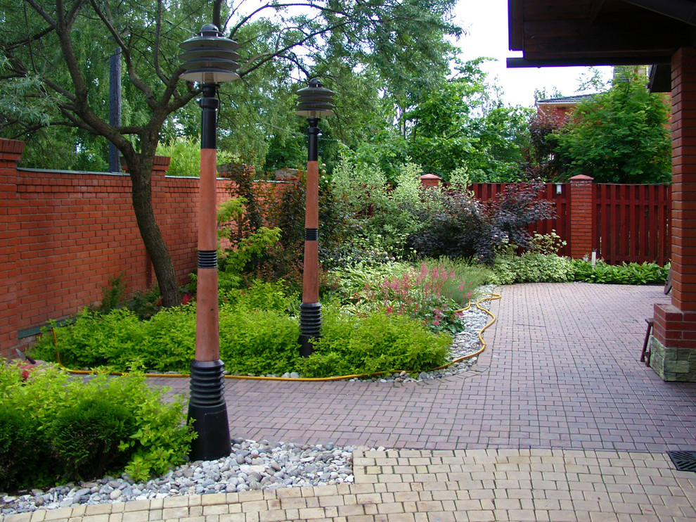 На фото: маленький летний участок и сад на переднем дворе в современном стиле с полуденной тенью, мощением тротуарной плиткой, подъездной дорогой и садовой дорожкой или калиткой для на участке и в саду