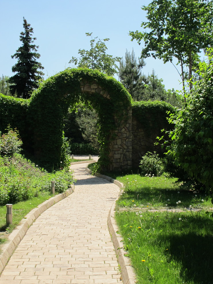 Inspiration för moderna trädgårdar i delvis sol, med en trädgårdsgång och marksten i tegel