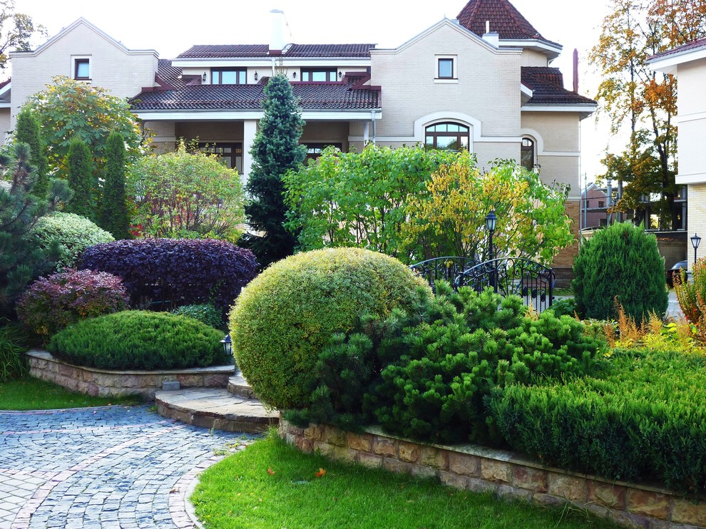 На фото: участок и сад в классическом стиле с подпорной стенкой с