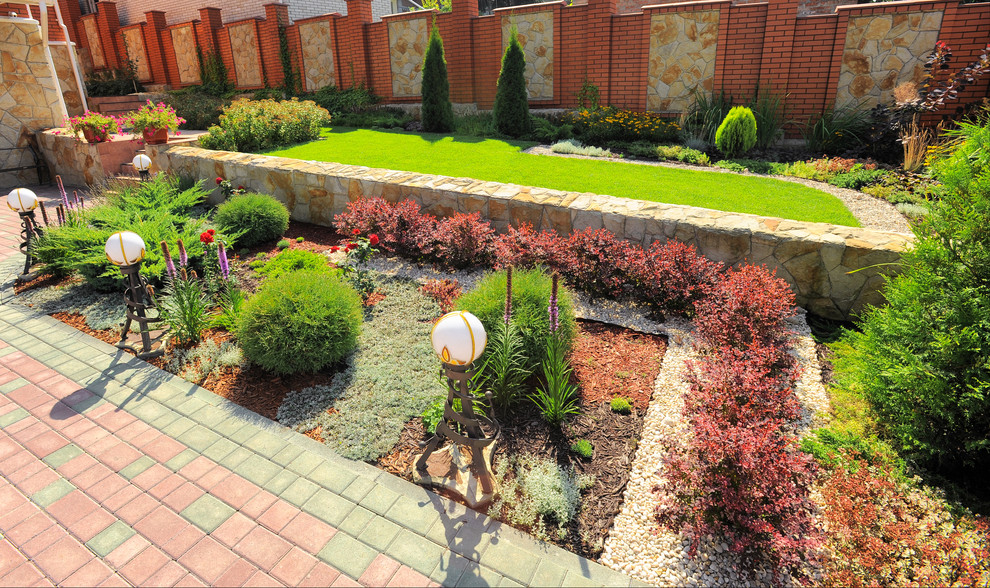 Diseño de jardín clásico en verano con jardín francés, exposición total al sol, muro de contención y adoquines de ladrillo