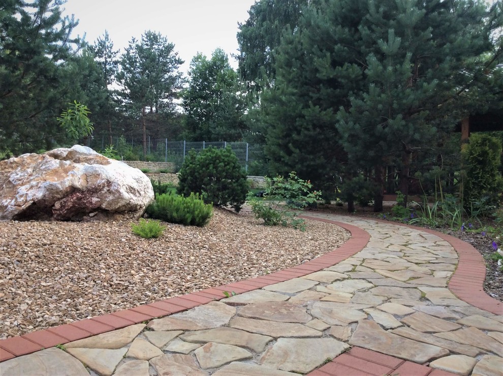 Cette image montre un aménagement d'entrée ou allée de jardin traditionnel de taille moyenne et l'été avec une exposition partiellement ombragée et des pavés en pierre naturelle.