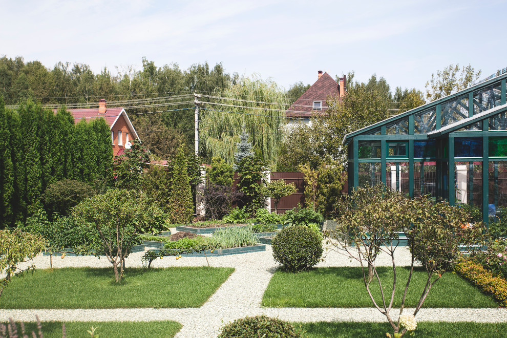 Diseño de camino de jardín clásico en verano en patio trasero con exposición total al sol, gravilla y jardín francés
