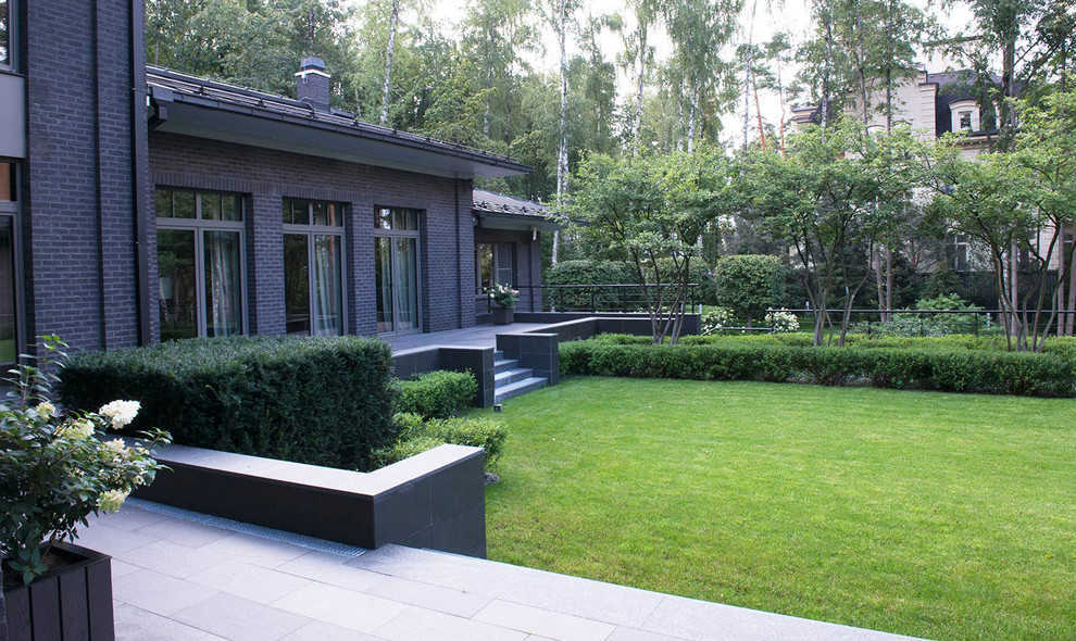 Стильный дизайн: летний регулярный сад на внутреннем дворе в современном стиле с полуденной тенью, подпорной стенкой и покрытием из каменной брусчатки - последний тренд