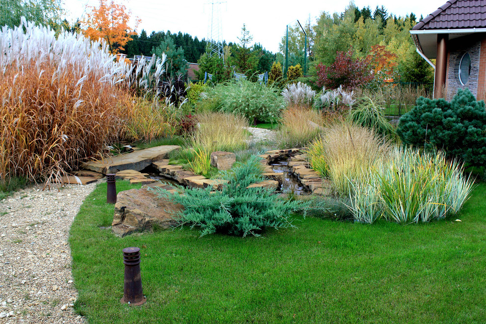 Idee per un giardino xeriscape moderno esposto in pieno sole di medie dimensioni e in cortile in autunno con sassi e rocce e ghiaia