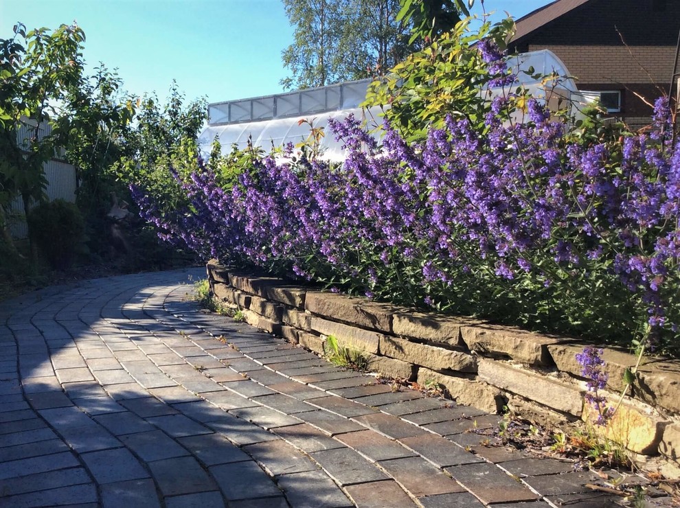 Esempio di un giardino esposto a mezz'ombra di medie dimensioni in estate con un muro di contenimento e pavimentazioni in mattoni