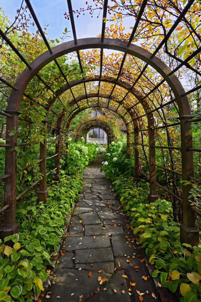 Exempel på en klassisk trädgård i delvis sol på hösten, med en trädgårdsgång