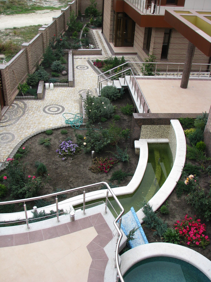 Ispirazione per un giardino formale moderno esposto in pieno sole di medie dimensioni e in cortile in estate con un muro di contenimento e pavimentazioni in cemento