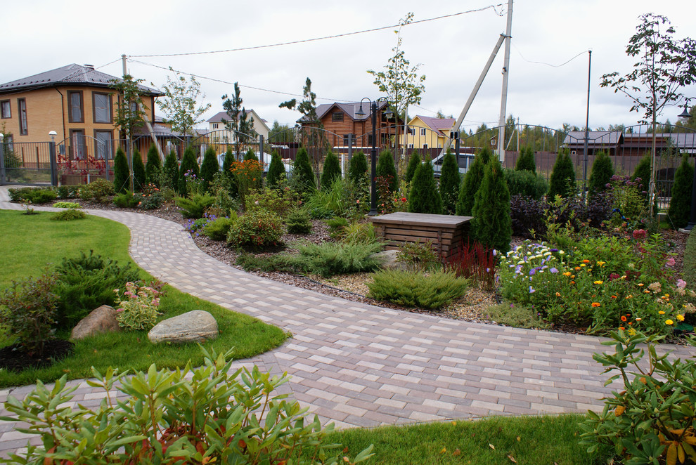На фото: большой участок и сад на переднем дворе в современном стиле с садовой дорожкой или калиткой и мощением тротуарной плиткой