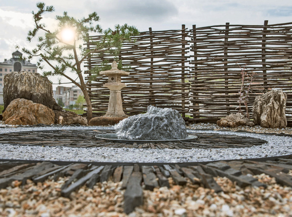 Photo of a small world-inspired full sun garden in Other with a water feature and gravel.