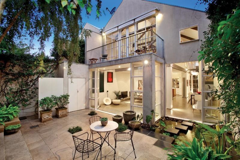 This is an example of a small urban back patio in Melbourne with a potted garden, natural stone paving and no cover.