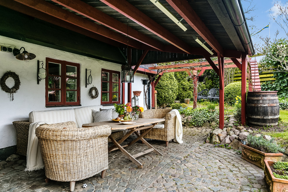 Idée de décoration pour une terrasse avec des plantes en pots latérale champêtre de taille moyenne avec des pavés en pierre naturelle et une extension de toiture.