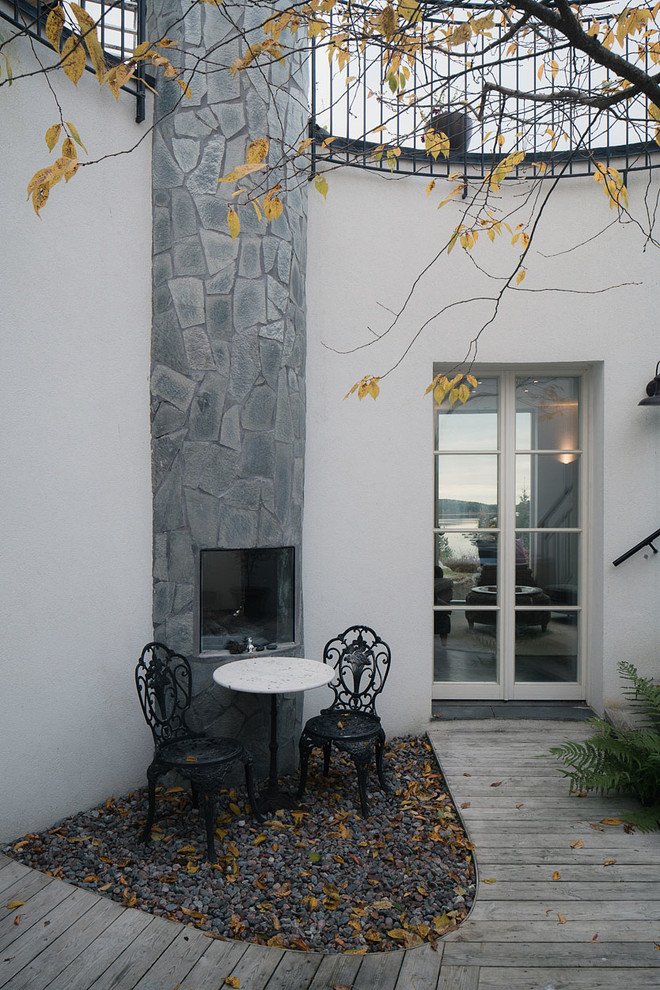 Ispirazione per un patio o portico nordico in cortile e di medie dimensioni con nessuna copertura, pedane e un caminetto