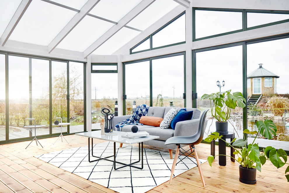 Ispirazione per una veranda scandinava di medie dimensioni con parquet chiaro e soffitto in vetro