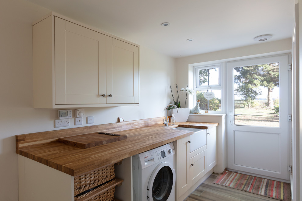 Medium sized traditional single-wall separated utility room in Berkshire with a belfast sink, shaker cabinets, beige cabinets, wood worktops, beige walls, brown floors and brown worktops.