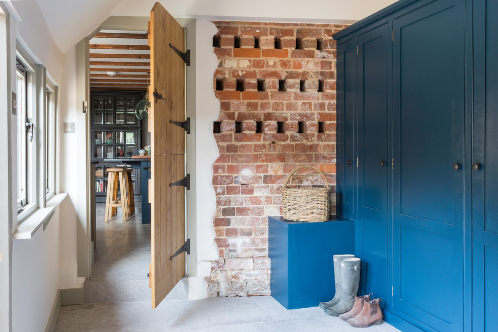 This is an example of a farmhouse single-wall utility room with shaker cabinets, blue cabinets and grey floors.