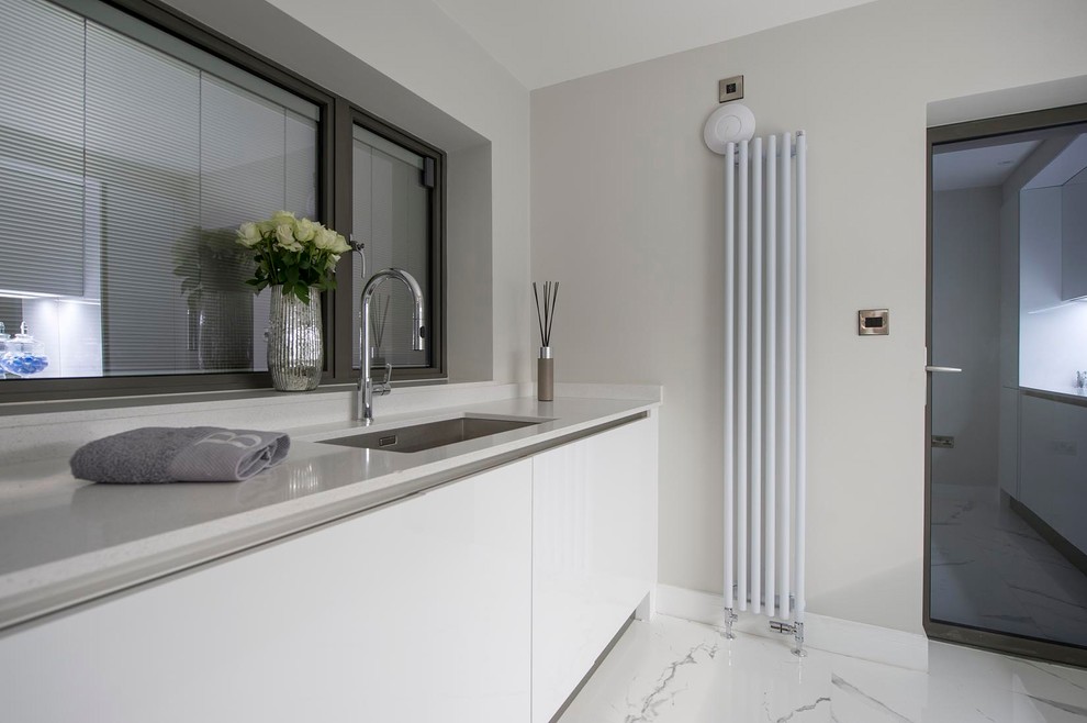 Inspiration for a small contemporary galley utility room in Other with a submerged sink, flat-panel cabinets, white cabinets, quartz worktops, beige walls, ceramic flooring, an integrated washer and dryer, white floors and white worktops.