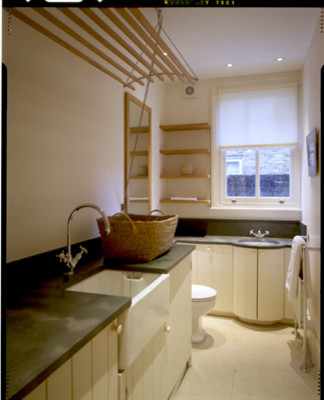 Inspiration pour une buanderie design avec un évier de ferme, un placard à porte shaker et un sol en calcaire.