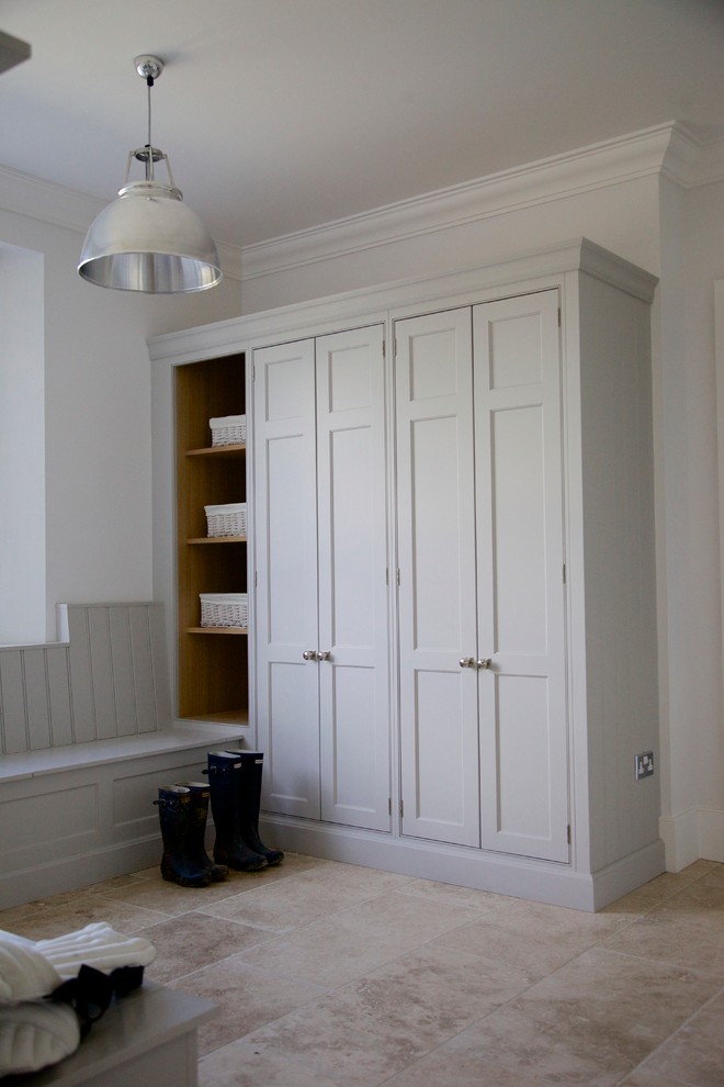 Exemple d'une buanderie chic en U de taille moyenne avec un placard à porte shaker, des portes de placard grises, un mur blanc et un sol en travertin.