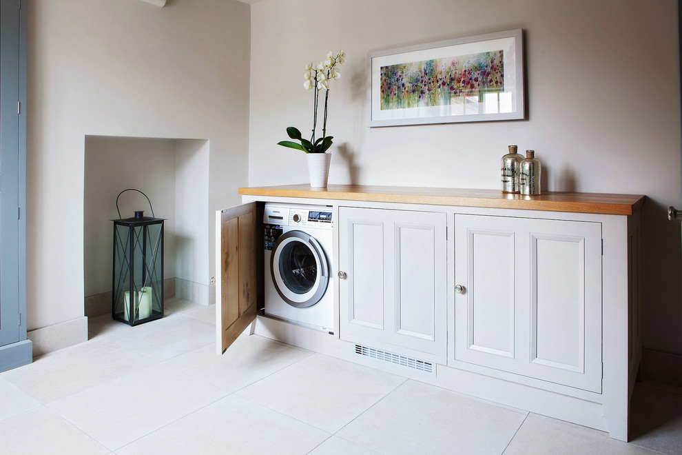 Foto de lavadero contemporáneo con puertas de armario grises, encimera de madera y armarios con paneles empotrados