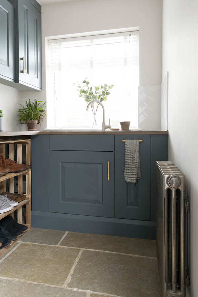 Ejemplo de lavadero rústico pequeño con puertas de armario azules, encimera de madera, suelo de piedra caliza, suelo gris y encimeras marrones