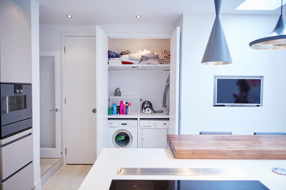 Moderner Hauswirtschaftsraum mit Waschmaschinenschrank und Waschmaschine und Trockner nebeneinander in Sussex