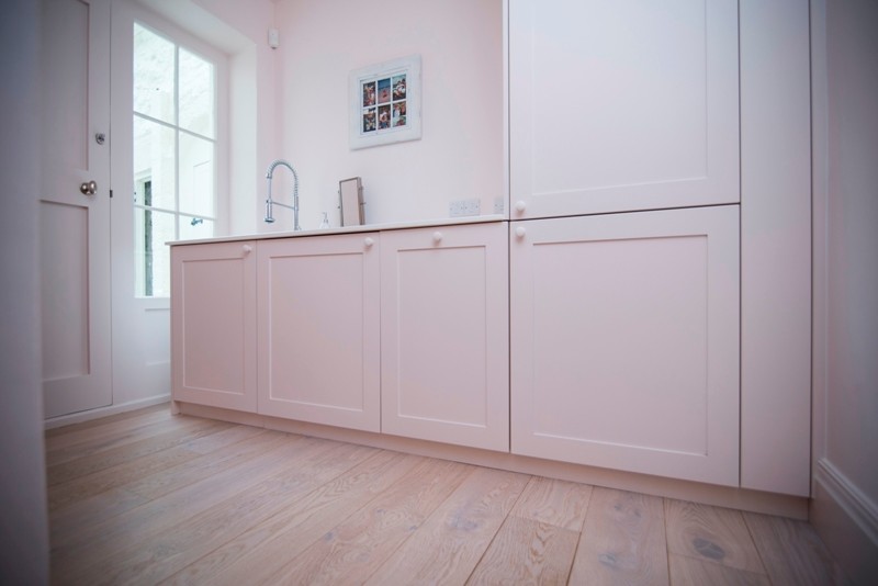 Mittelgroßer Klassischer Hauswirtschaftsraum mit weißer Wandfarbe, hellem Holzboden und braunem Boden in Sonstige