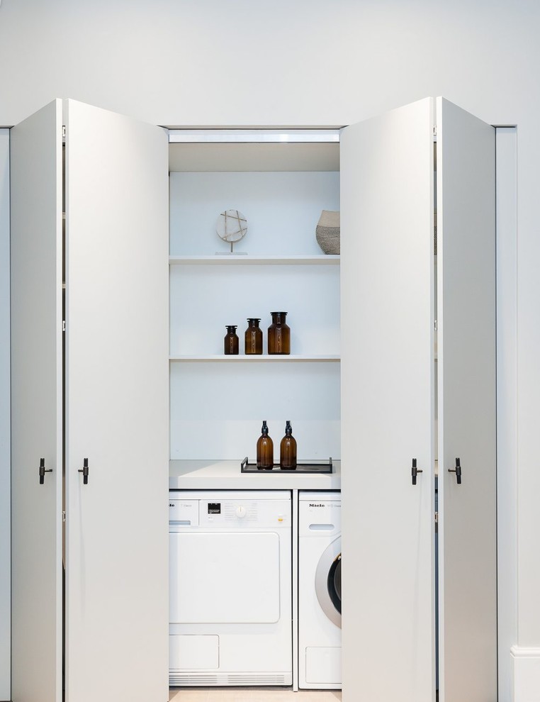 Design ideas for a contemporary single-wall laundry cupboard in Cornwall with open cabinets, white cabinets, a side by side washer and dryer and white worktops.