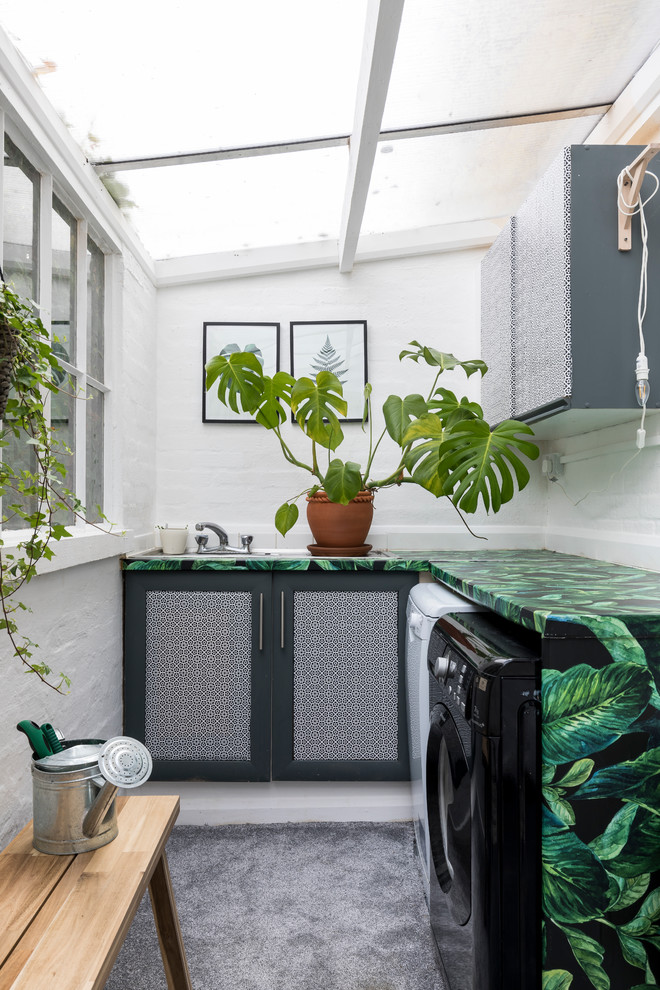 Stilmix Waschküche in L-Form mit Schrankfronten im Shaker-Stil, weißer Wandfarbe, Waschmaschine und Trockner nebeneinander und bunter Arbeitsplatte in London
