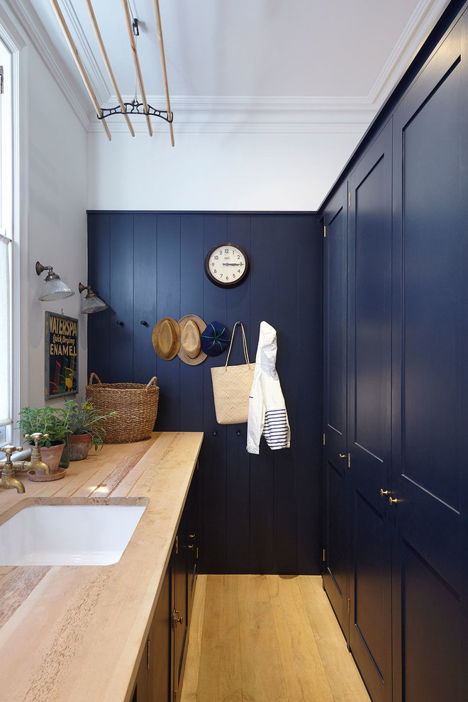 Zweizeilige, Kleine Klassische Waschküche mit Schrankfronten mit vertiefter Füllung, blauen Schränken, Arbeitsplatte aus Holz, hellem Holzboden, beigem Boden und beiger Arbeitsplatte in London