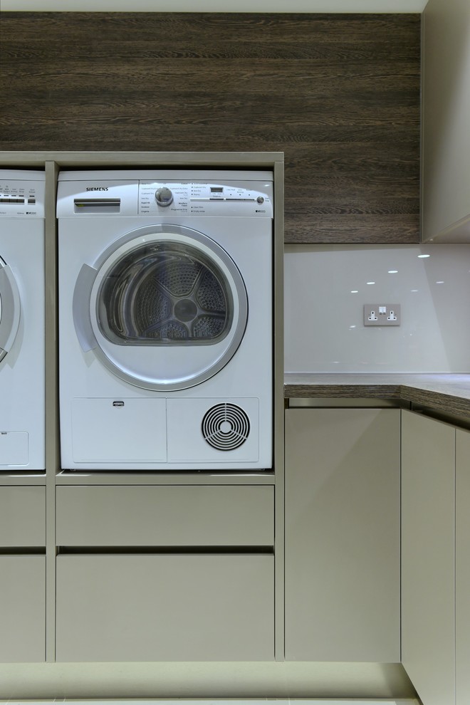 Idee per una lavanderia multiuso contemporanea di medie dimensioni con ante lisce, ante beige, top in superficie solida, pavimento in gres porcellanato e lavatrice e asciugatrice affiancate