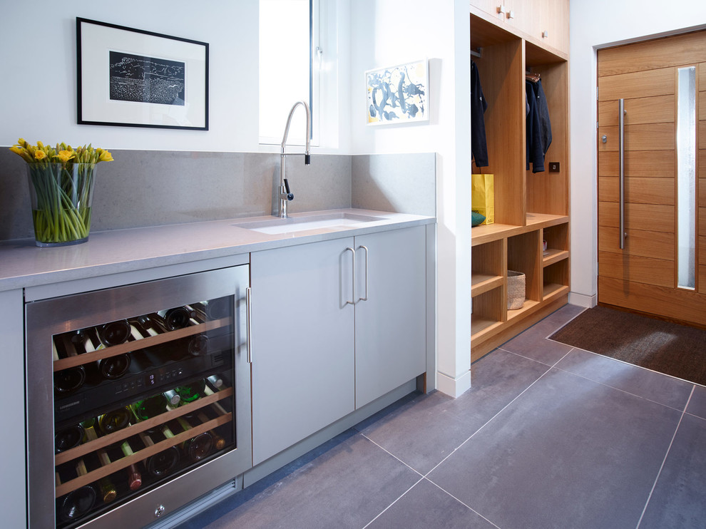 Multifunktionaler, Einzeiliger Moderner Hauswirtschaftsraum mit Waschbecken, flächenbündigen Schrankfronten, Mineralwerkstoff-Arbeitsplatte, weißer Wandfarbe und Keramikboden in Devon