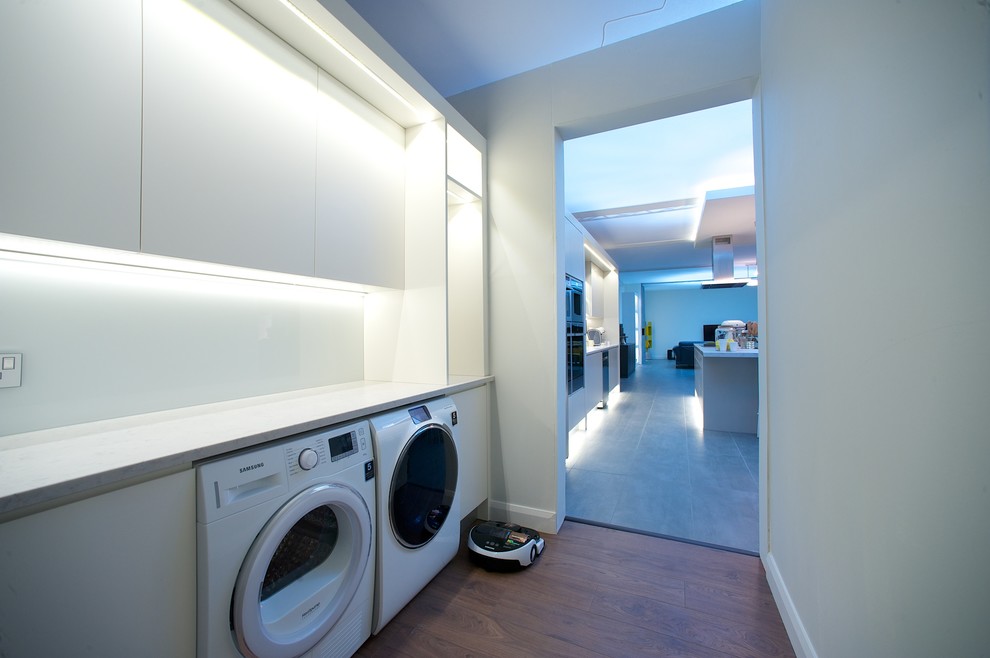 Idee per una lavanderia multiuso moderna di medie dimensioni con ante lisce, ante bianche, top in quarzite, pareti grigie, pavimento in legno massello medio e lavatrice e asciugatrice affiancate