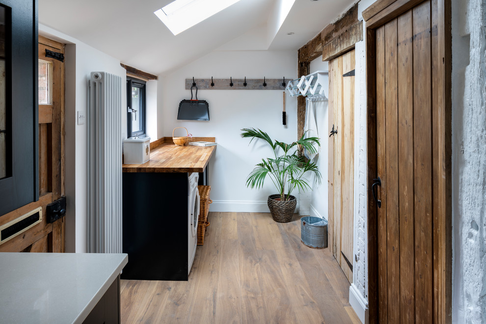 Inspiration for a small rural single-wall separated utility room in London with wood worktops, white walls, light hardwood flooring, beige floors and beige worktops.