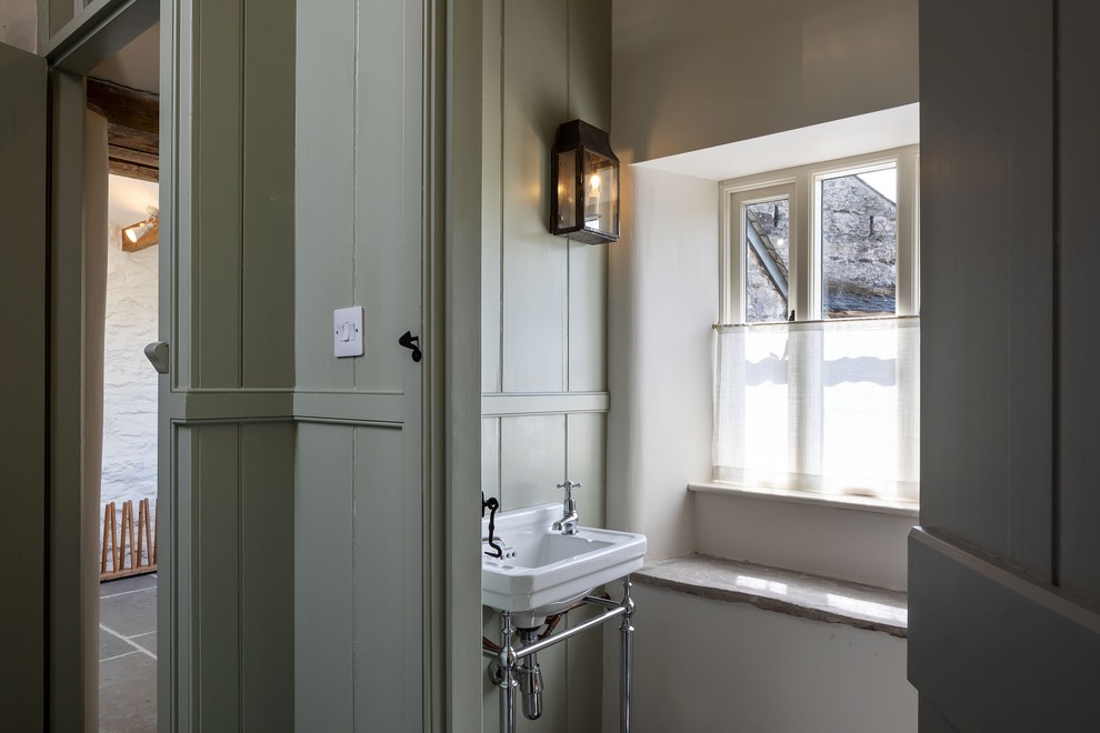 Inredning av en klassisk stor grå parallell grått tvättstuga enbart för tvätt, med en rustik diskho, skåp i shakerstil, gröna skåp, granitbänkskiva, vita väggar, skiffergolv, tvättmaskin och torktumlare byggt in i ett skåp och blått golv
