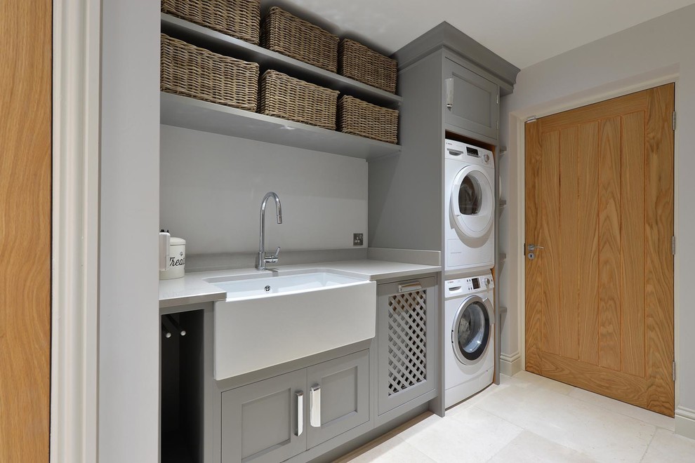 This is an example of a medium sized contemporary single-wall separated utility room in Other with a belfast sink, shaker cabinets, grey cabinets, granite worktops, grey walls, marble flooring and a stacked washer and dryer.