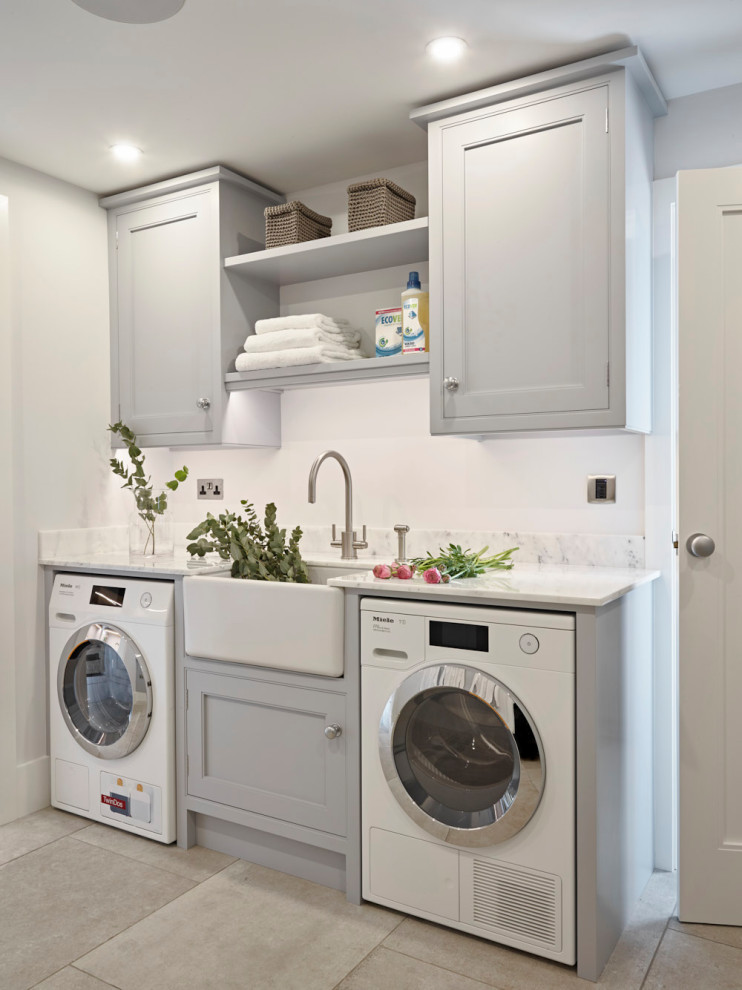 Modelo de cuarto de lavado lineal actual pequeño con fregadero sobremueble, armarios con rebordes decorativos, puertas de armario grises, encimera de mármol, paredes grises y encimeras blancas